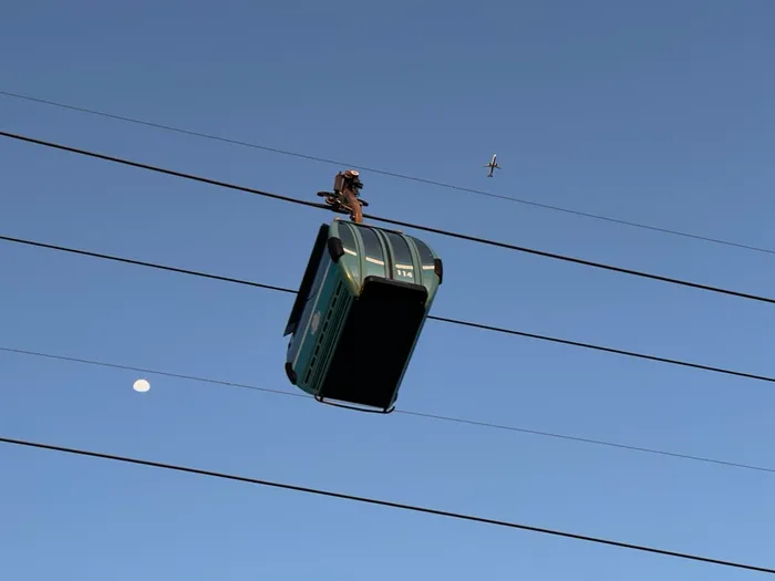 A shot of Disney's Skyliner transportation system from below with an airliner in the sky above.